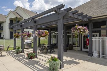 A patio with a pergola and flowers in pots.